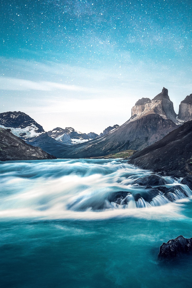 Быстрая вода к реке у гор на фоне голубого неба 