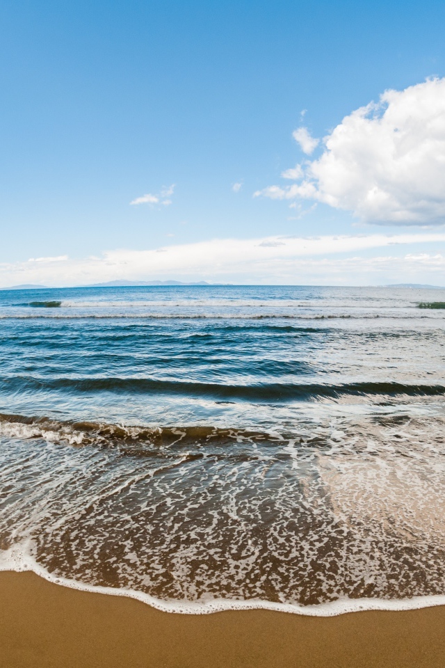 Морская волна на песке под красивым небом с белыми облаками