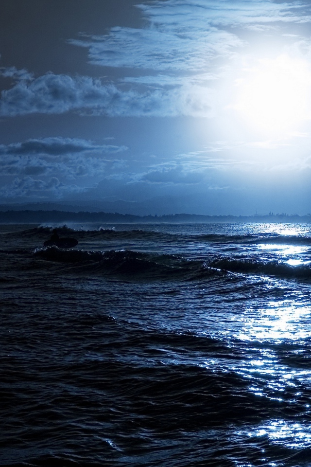 Яркая луна освещает волны на берегу моря