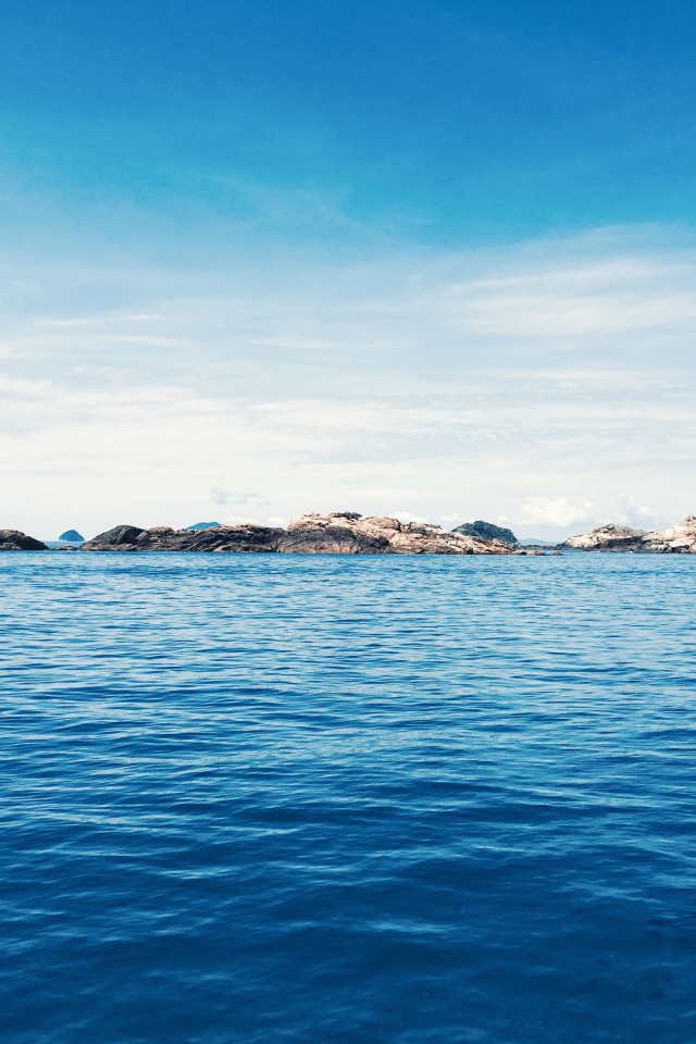 Спокойное синее море со скалами на горизонте