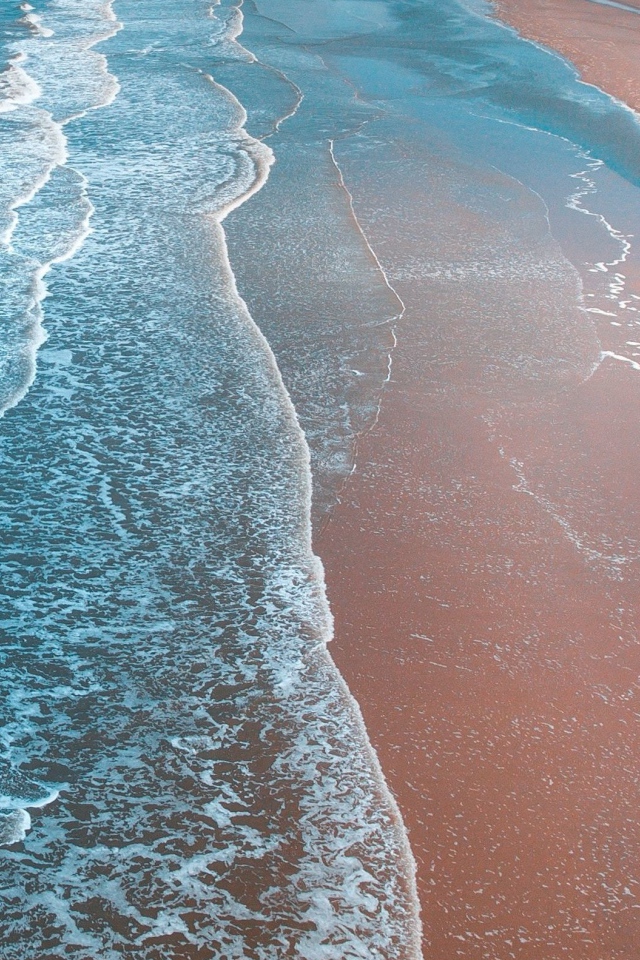 Gentle white waves wash the sandy coast of the ocean