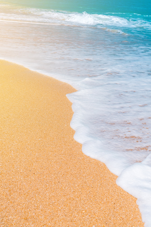 Белые волны голубого океана на желтом песке 