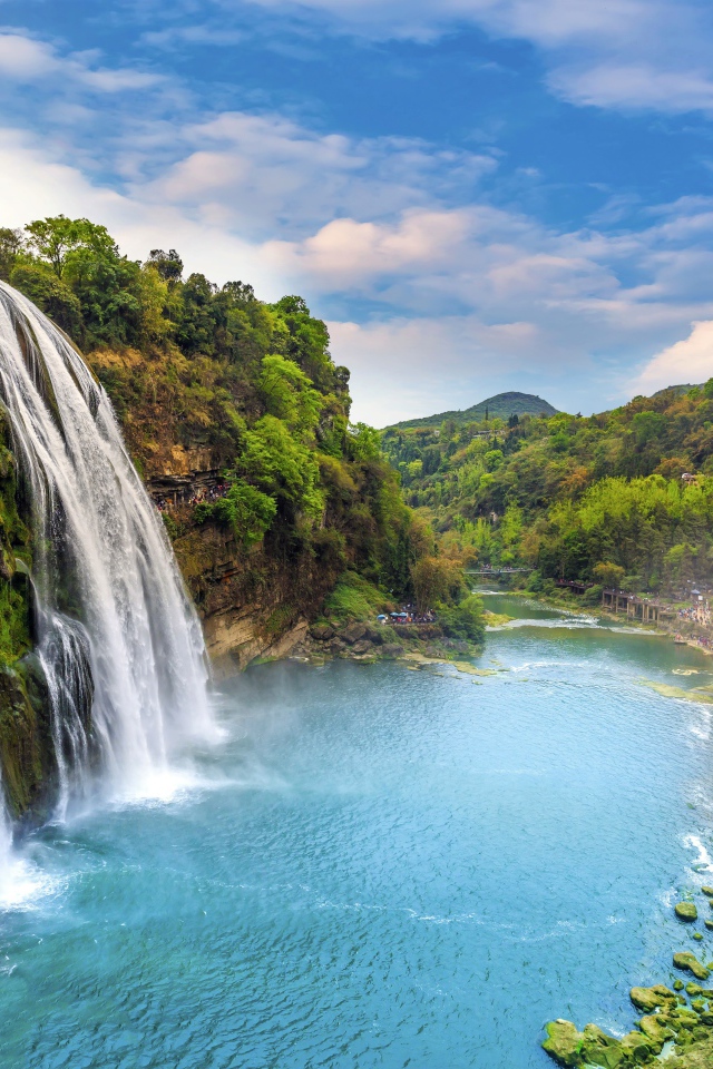 Красивый водопад стекает с утеса под голубым небом