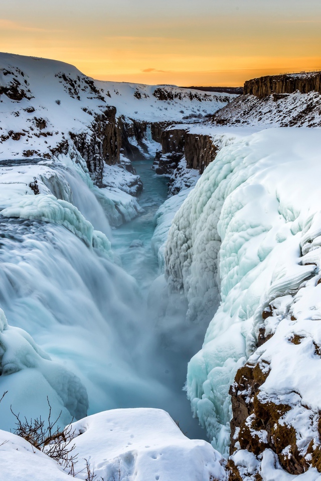 Заледеневший водопад у покрытых снегом берегов, Исландия