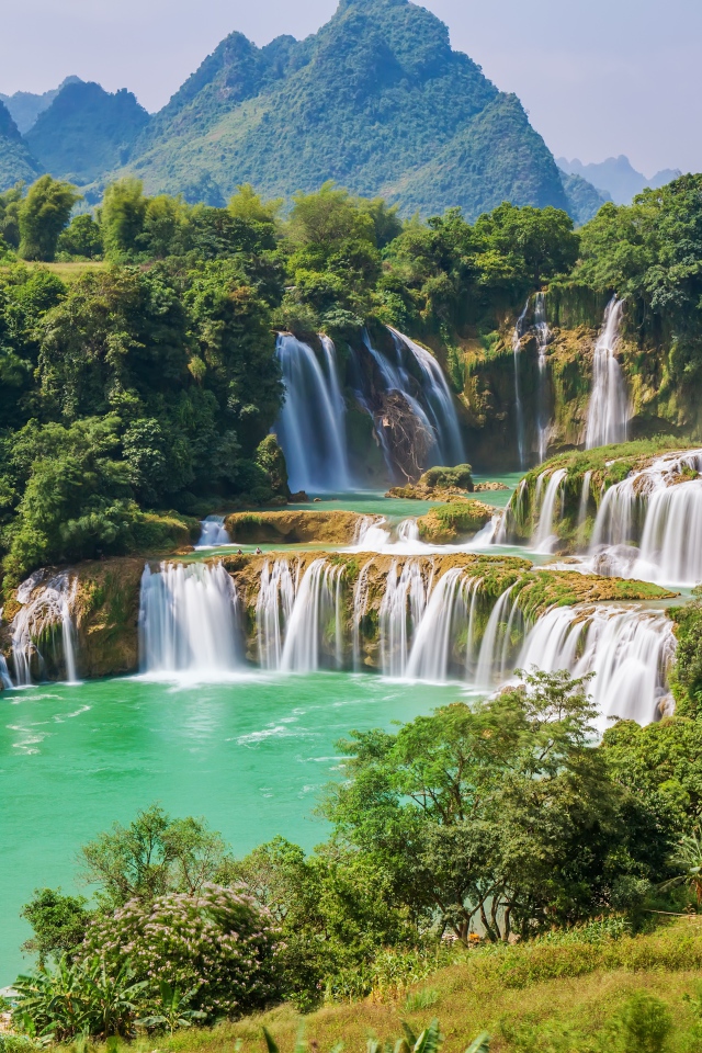 Водопад стекает с гор на фоне зеленой природы