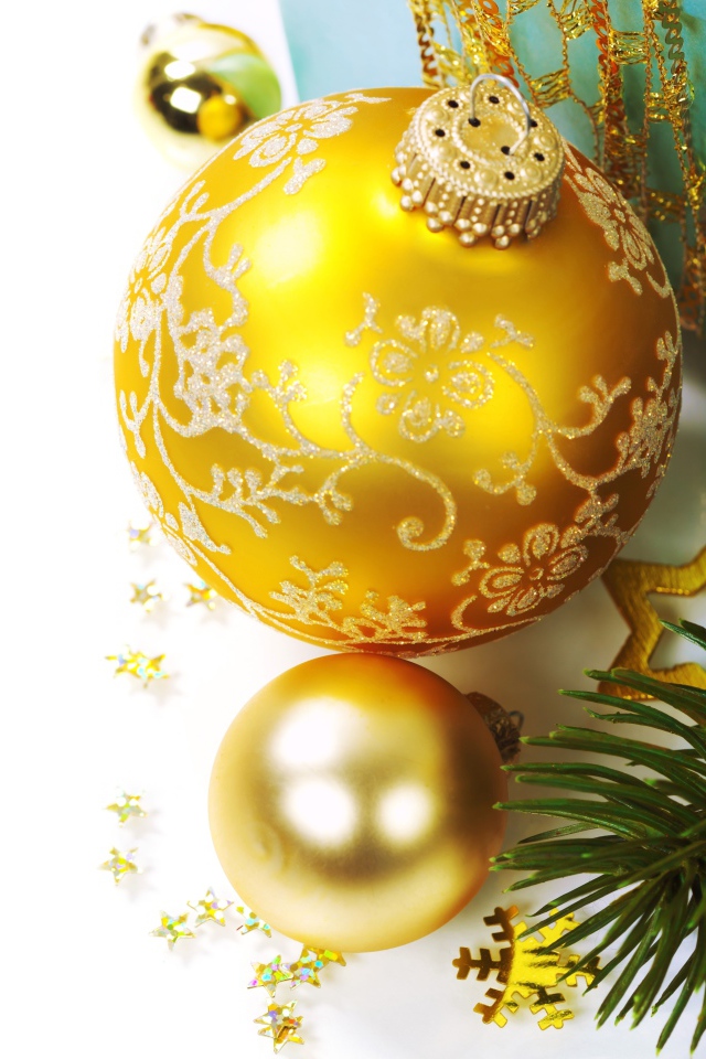 Красивые золотые елочные шары с зеленой еловой веткой на белом фоне