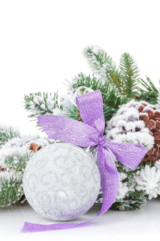 Серый елочный шар с бантом на зеленой ветке на Новый год 2019