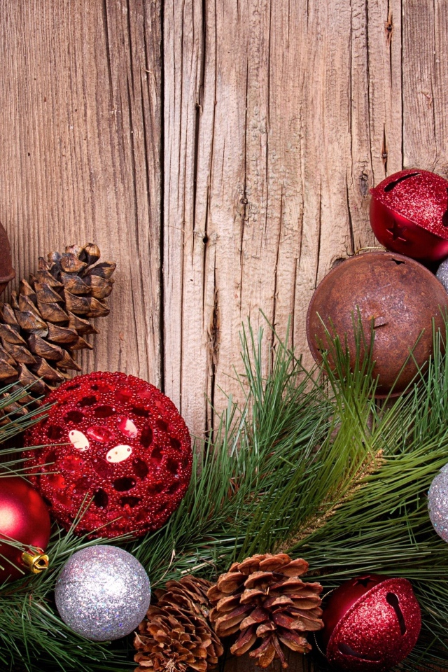 Зеленая еловая ветка с шишками и игрушками на деревянном фоне