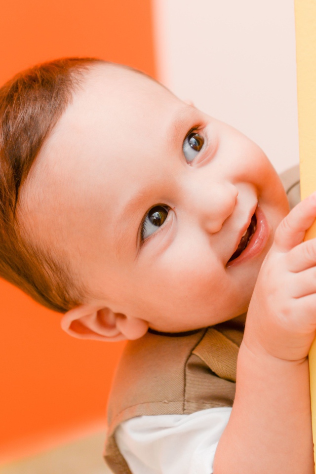 Маленький любопытный мальчик выглядывает из-за стены