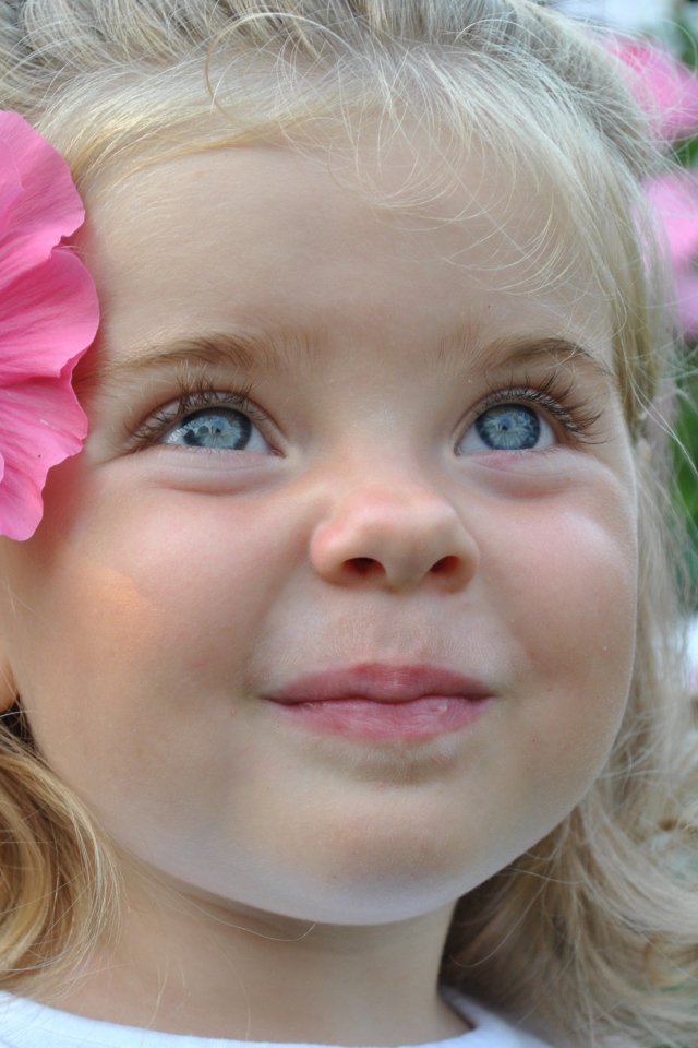 Милая маленькая девочка блондинка с цветком в волосах