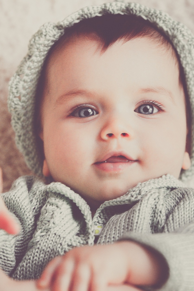 Маленький милый голубоглазый малыш в вязаном костюме