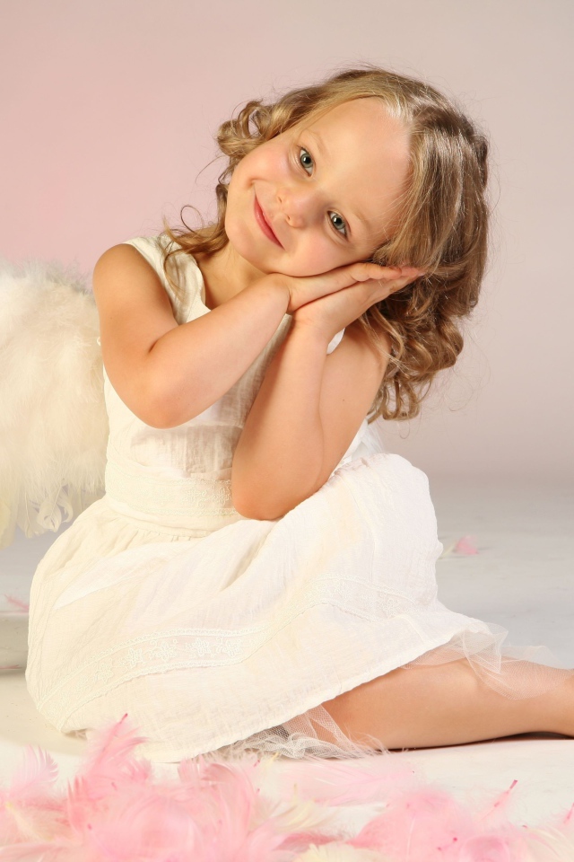 Милая маленькая девочка в белом платье с крыльями ангела
