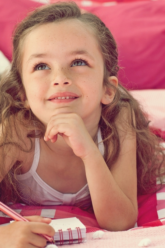 Замечтавшаяся маленькая девочка лежит на кровати