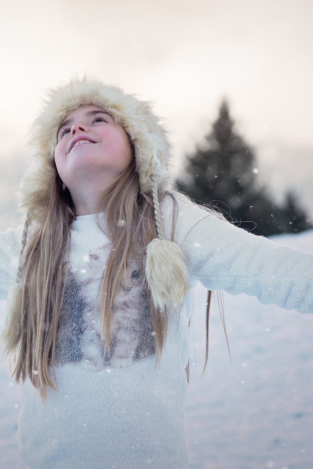 Девочка в белой шапке радуется снегу
