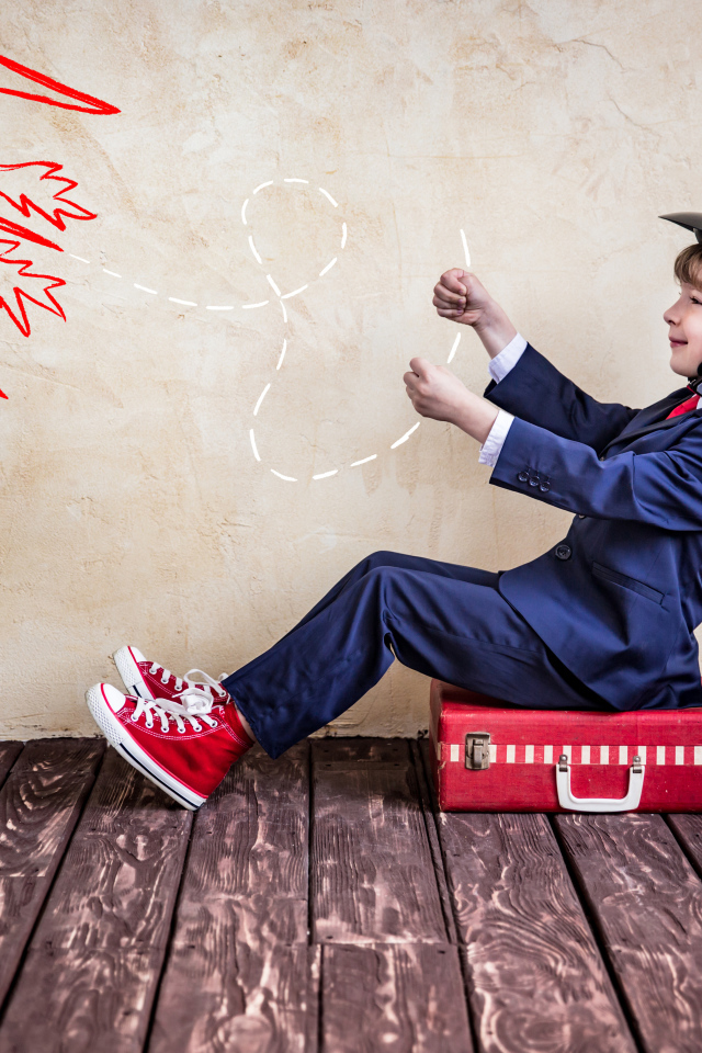 Маленький мальчик в шлеме сидит на чемодане