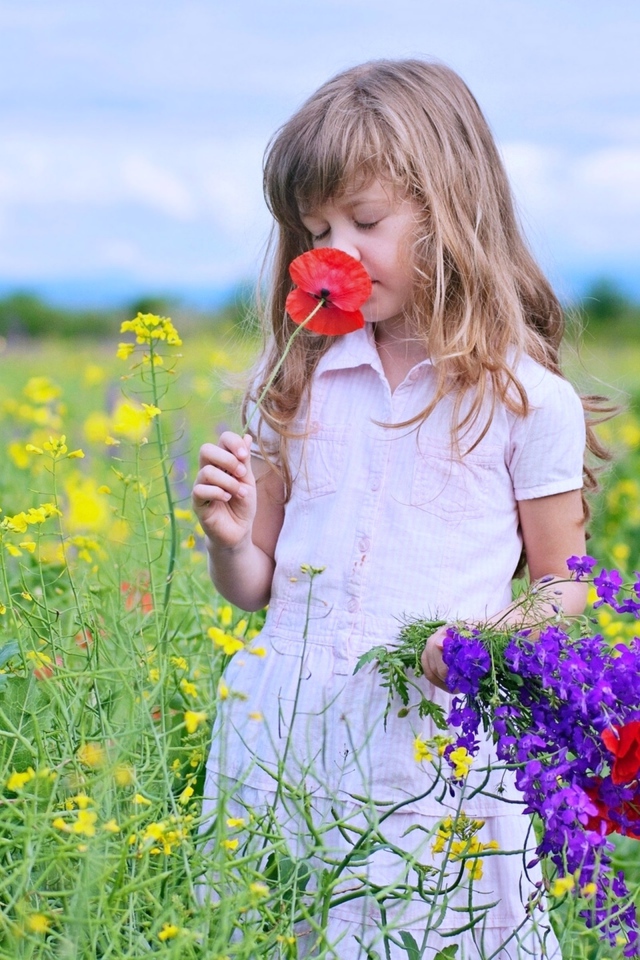 Маленькая девочка собирает на поле полевые цветы