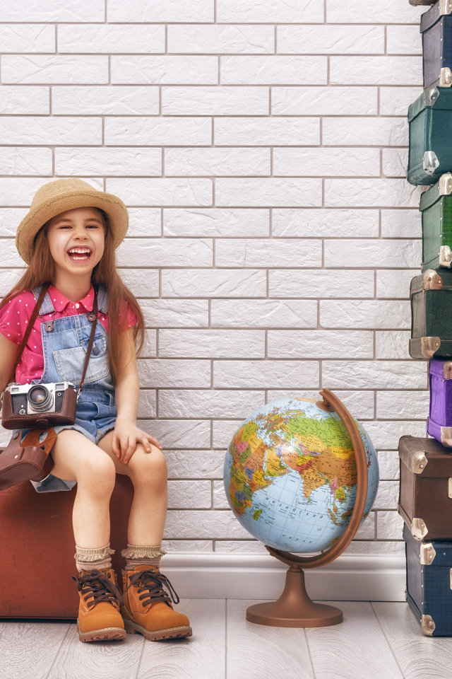 Маленькая девочка с фотоаппаратом сидит на чемодане