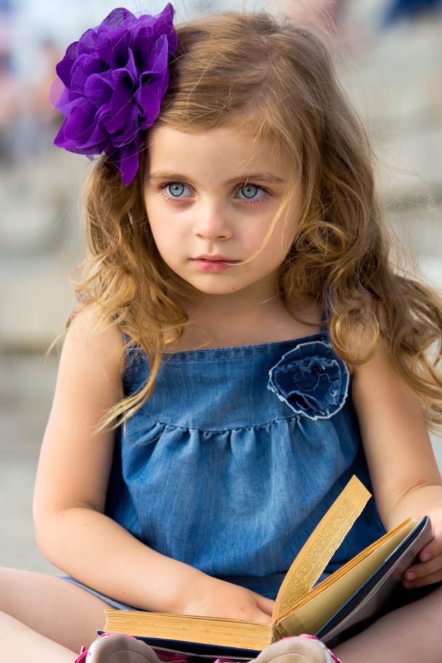 Маленькая девочка с цветком в волосах сидит на ступенях