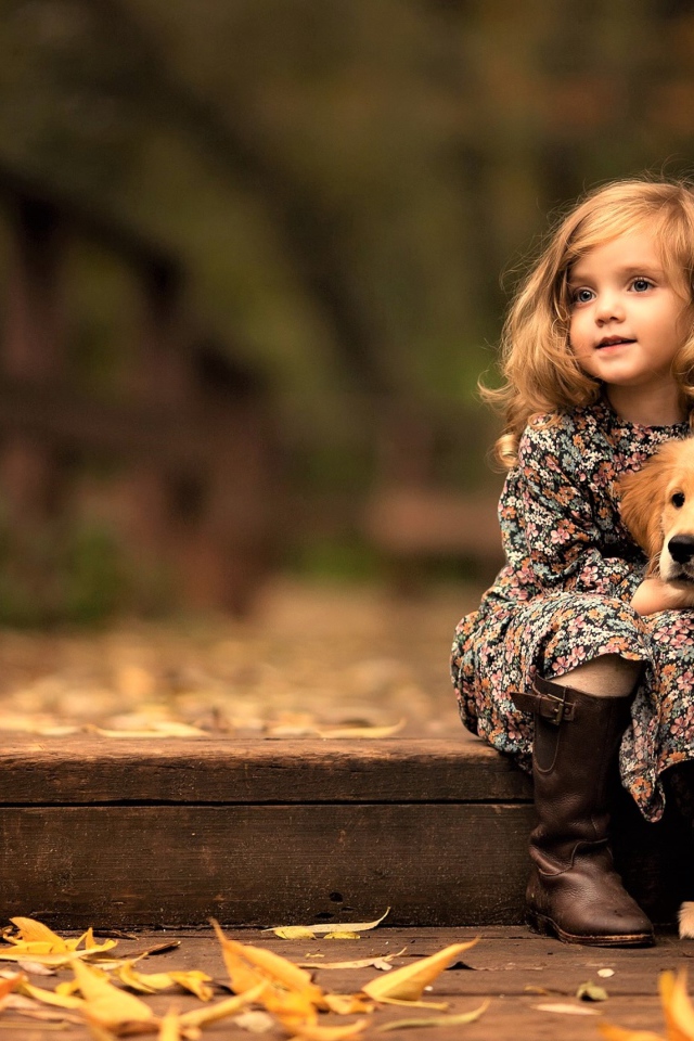 Маленькая девочка с золотистым ретривером сидит на мосту