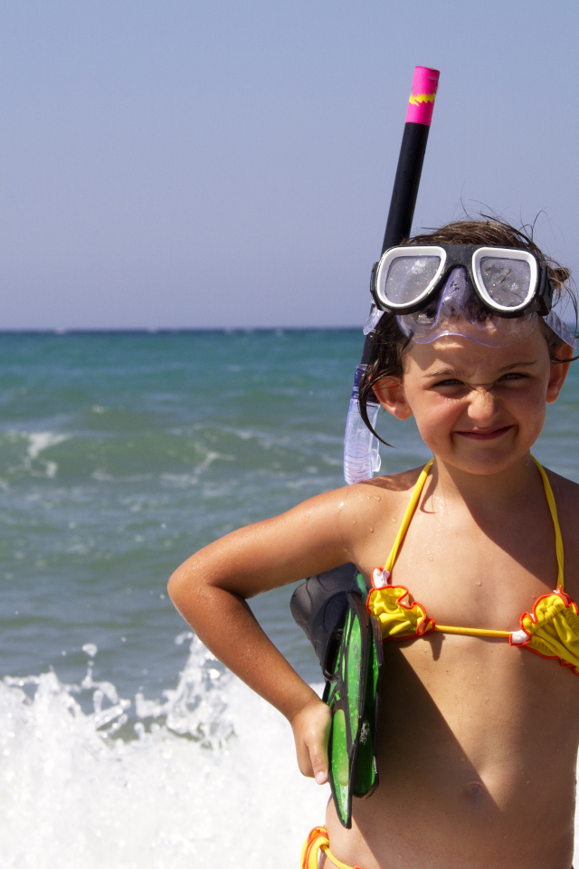Маленькая девочка в очках и с ластами на море