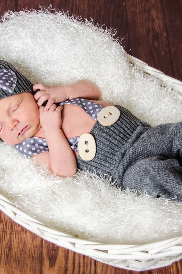 Спящий младенец в сером костюме в белой корзине