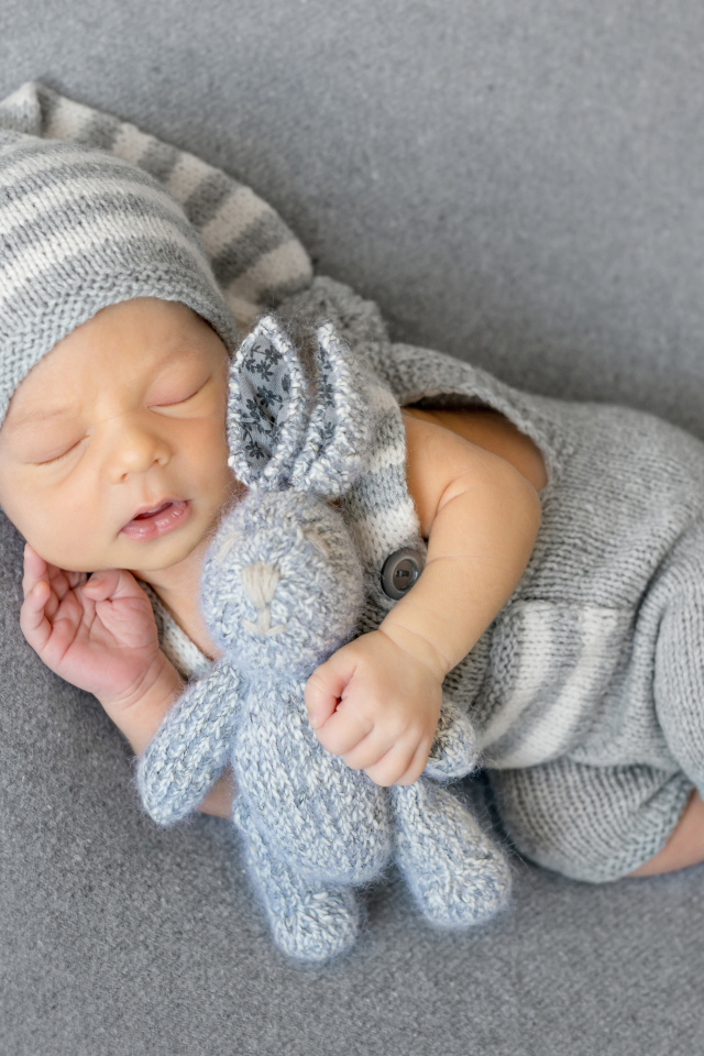 Спящий младенец с серым вязаным зайцем