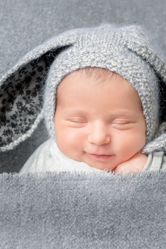 Маленький грудной ребенок в серой шапке с ушками