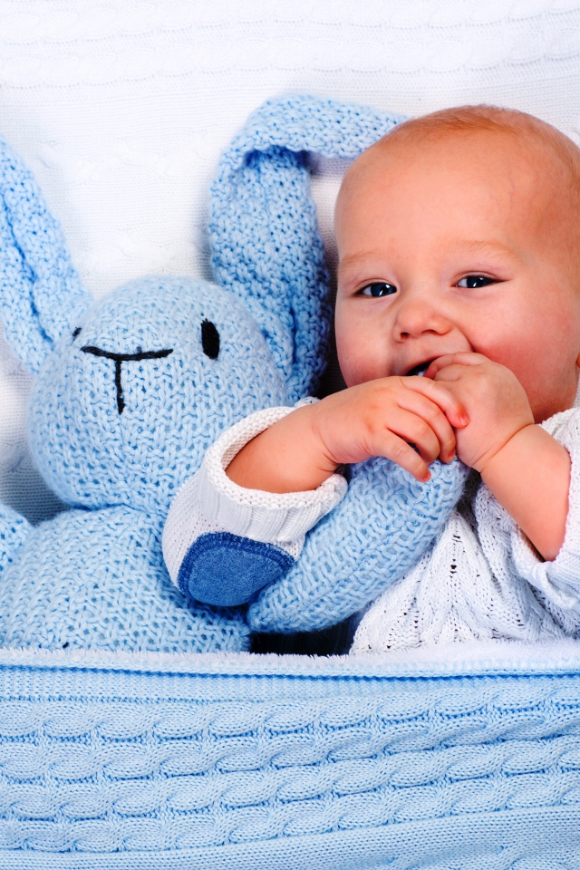 Маленький грудной ребенок грызет мягкую игрушку 