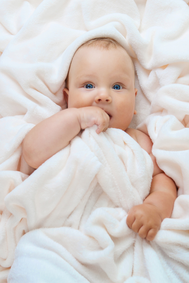 Маленький голубоглазый ребенок в покрывале 