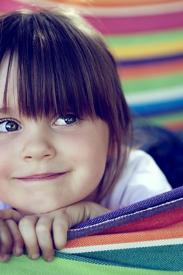 Маленькая кареглазая девочка лежит в гамаке