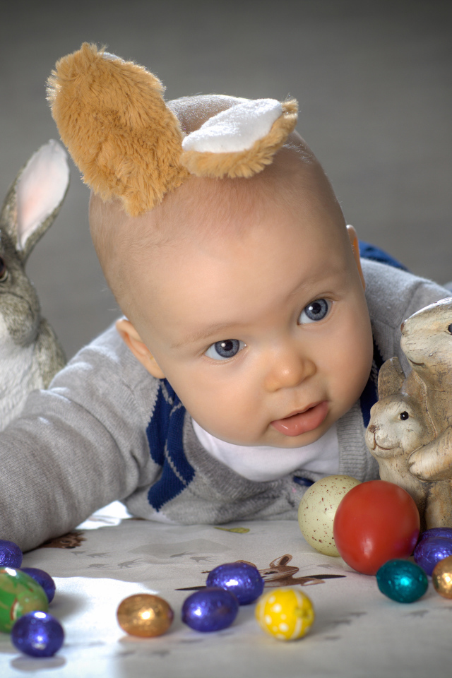 Маленький ребенок с пасхальными кроликами и яйцами