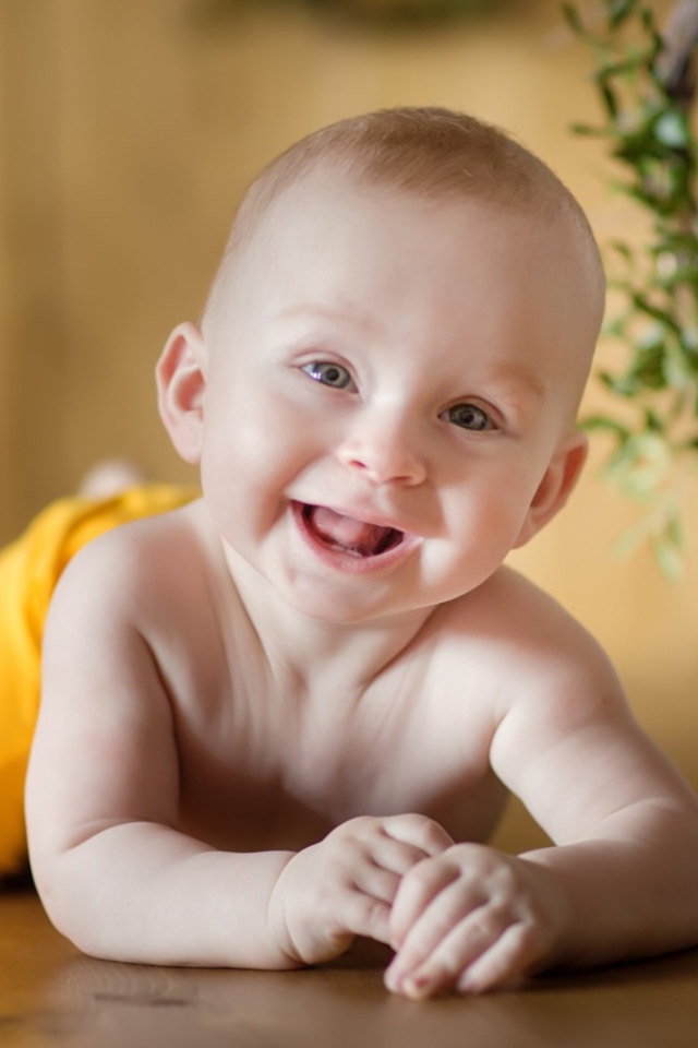 Улыбающийся малыш лежит на деревянном полу