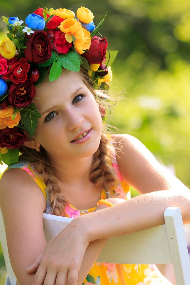 Красивая девочка с венком на голове сидит на стуле