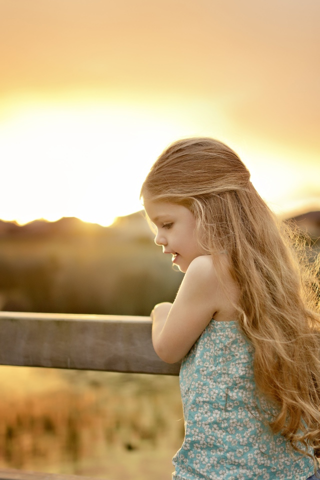 Красивая маленькая девочка на закате солнца