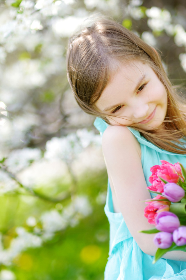 Красивая маленькая девочка с букетом тюльпанов весной