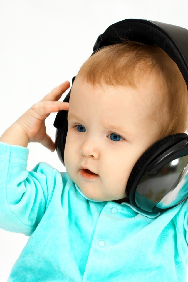 Голубоглазый мальчик в больших наушниках на белом фоне