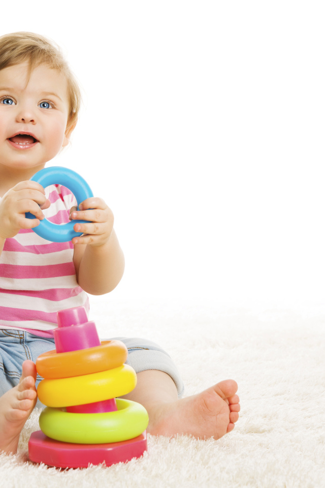 Голубоглазый маленький мальчик с игрушкой на белом фоне