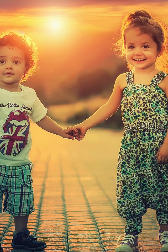 Счастливые мальчик и девочка на дороге на фоне заката