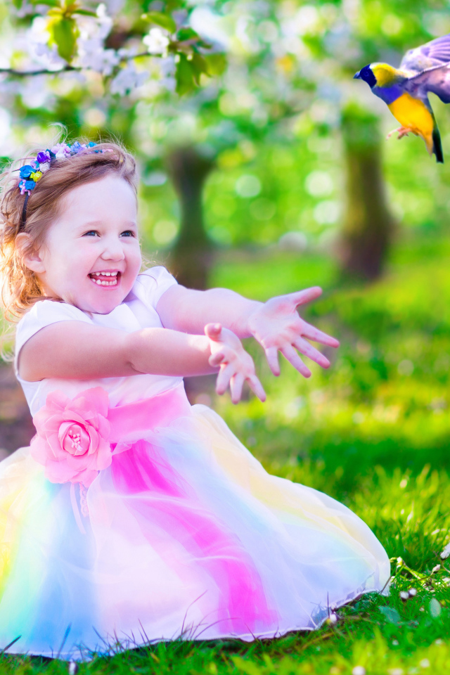 Смеющаяся маленькая девочка в красивом платье на зеленой траве