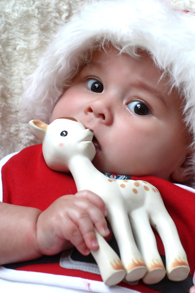 Маленький ребенок в новогодней шапке с игрушкой в руке