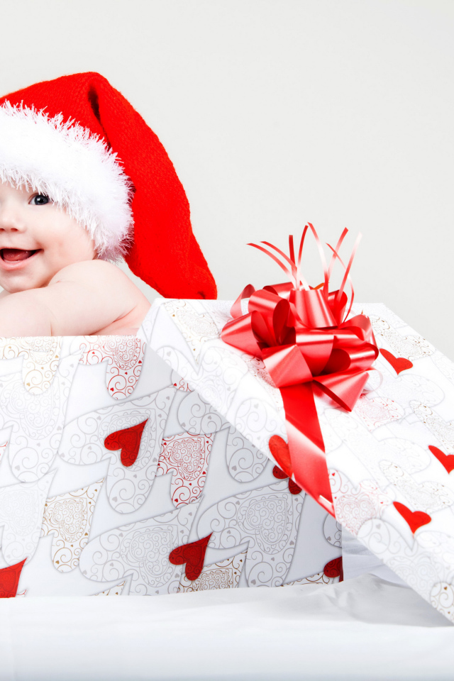 Маленький ребенок в новогоднем костюме в коробке для подарка на сером фоне