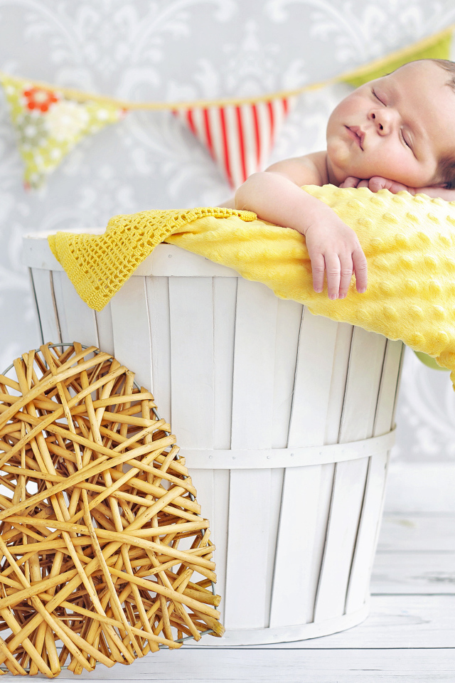 Маленький ребенок спит в корзине с плетеным сердцем