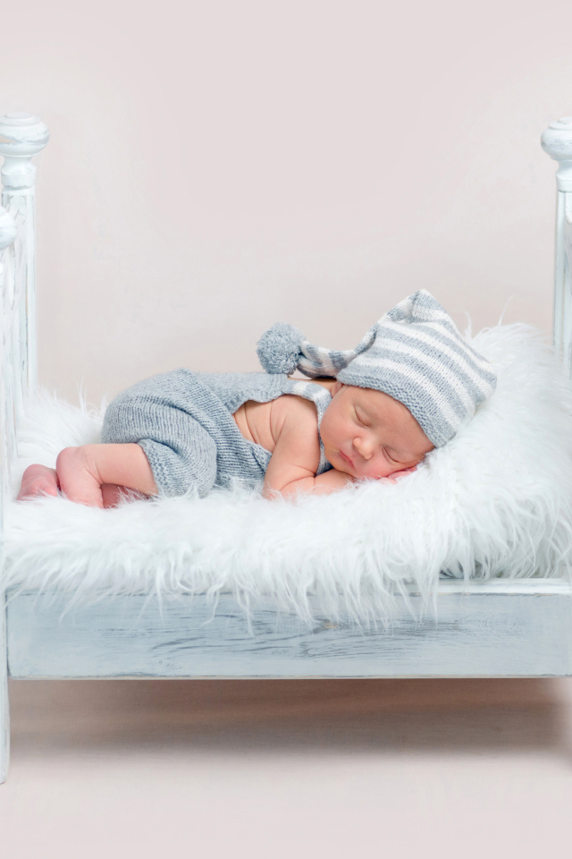 Маленький грудной ребенок спит в маленькой кроватке