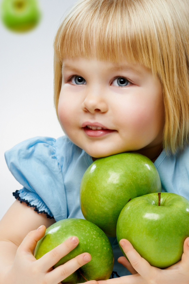 Маленькая девочка блондинка с зелеными яблоками