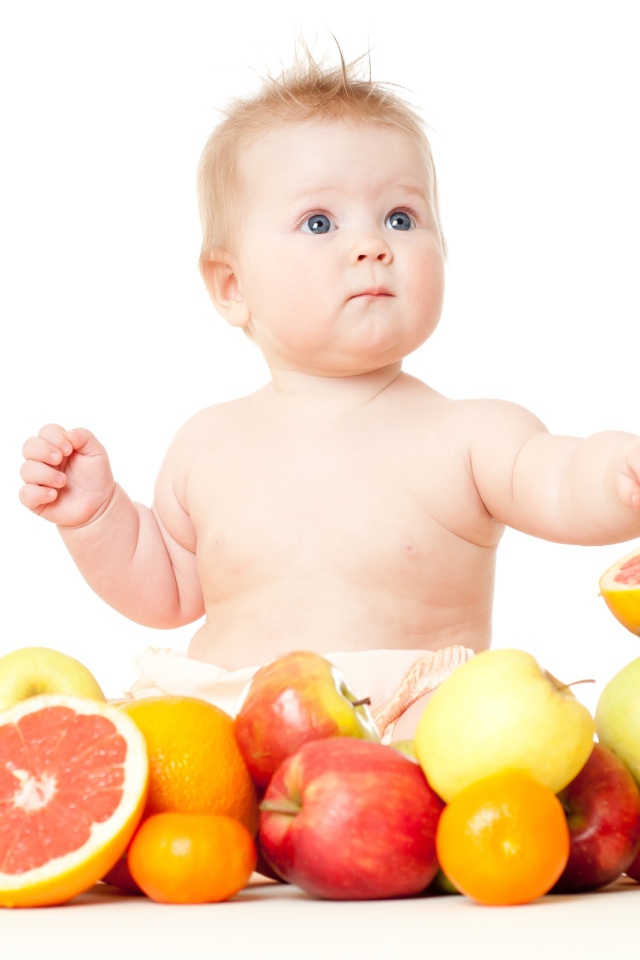 Маленький голубоглазый ребенок с фруктами на белом фоне