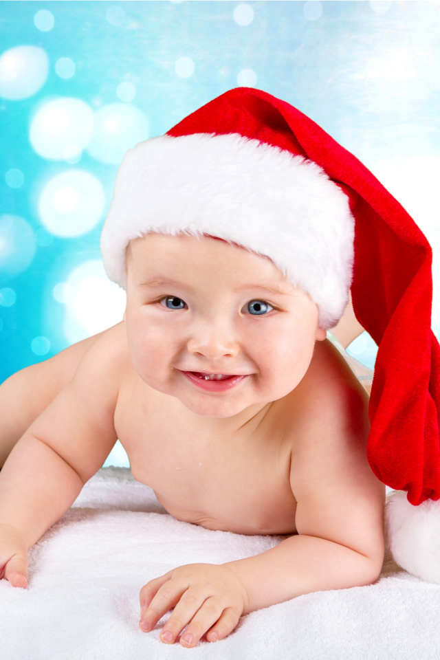 Маленький голубоглазый ребенок в красном новогоднем колпаке
