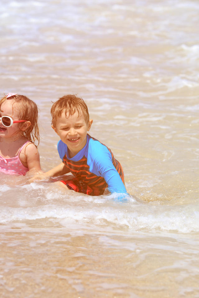 Маленькие мальчик и девочка купаются в море 