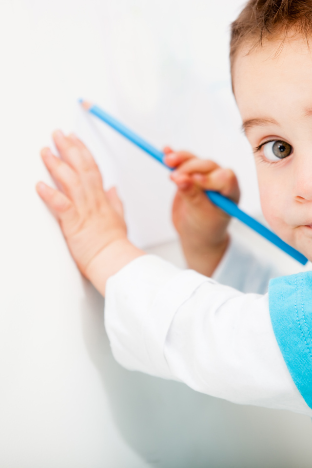 Маленький мальчик рисует карандашом на стене