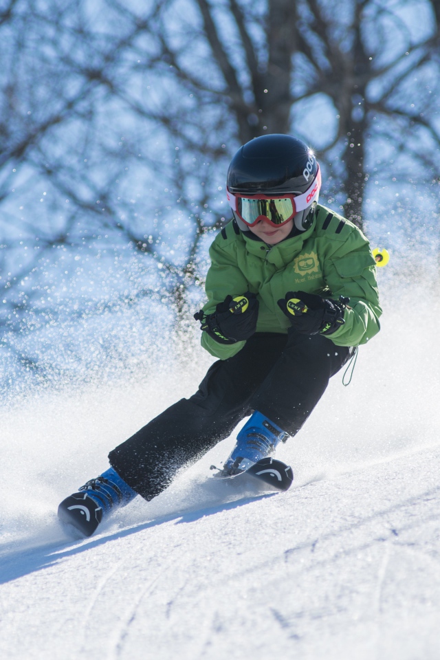Маленький мальчик спускается с горы на лыжах