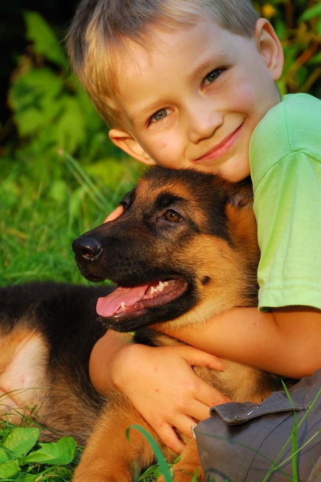 Маленький мальчик обнимает щенка немецкой овчарки